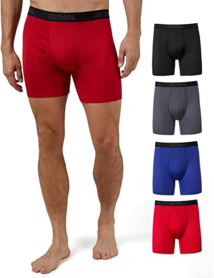 Man wearing red boxer briefs, standing barefoot. Four additional boxers in black, gray, blue, and red are displayed next to him, showcasing variety.