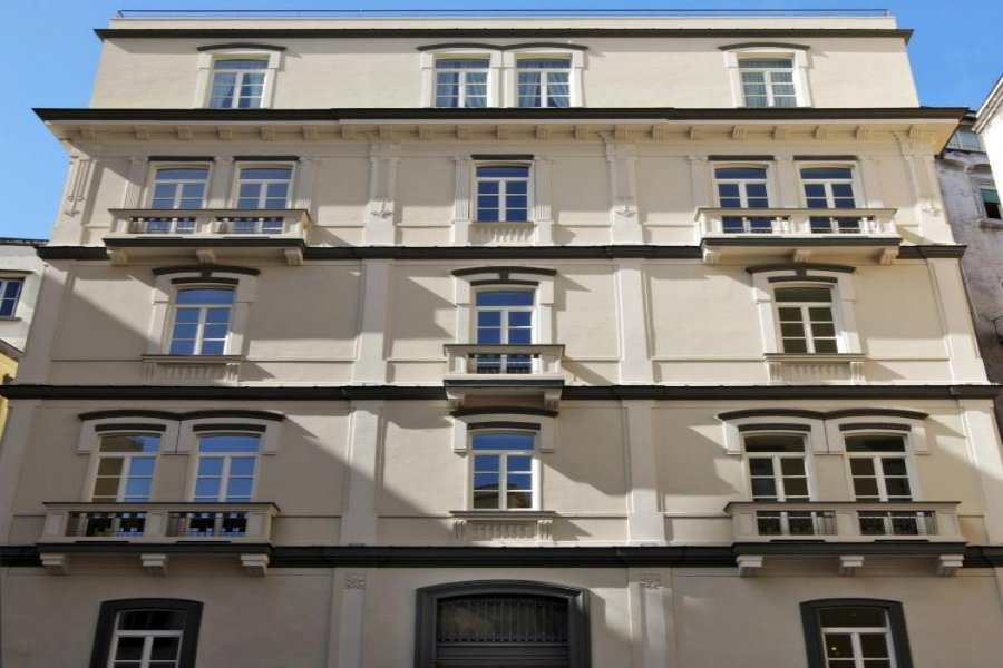 Five-story cream Palazzo Decumani facade with classical windows, balconies, and string courses.