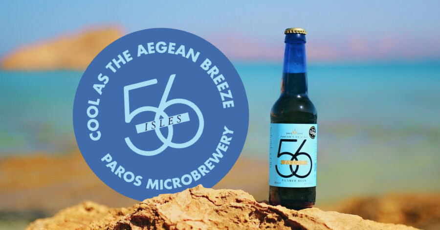 Greek beer bottle on Paros beach with Aegean Sea, labeled 56 Isles Paros Microbrewery.