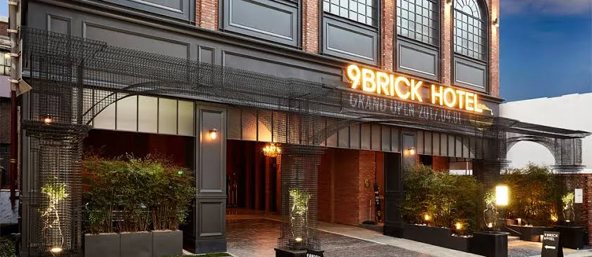Nine Brick Boutique Hotel entrance with illuminated sign, brick facade, courtyard and warm evening lighting.