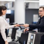 Friendly woman staff taking passport from passenger at airport check in