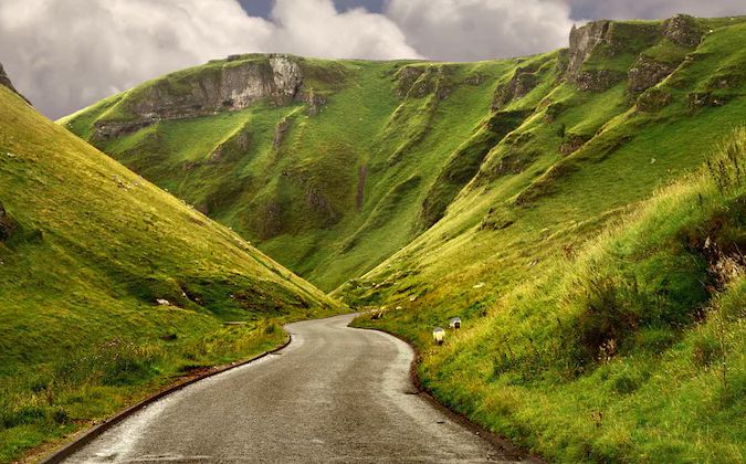 Scenic Peak District road in between lush mountains