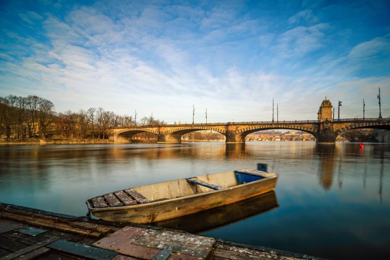 Sunrise view at Vltava river bridge and boat with clear water reflection