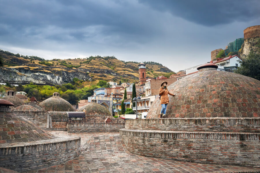Traveler exploring the historic Abanotubani district in Tbilisi, surrounded by traditional architecture and vibrant streets.