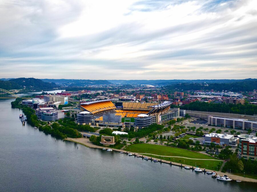 Aerial view of Pittsburgh, Pennsylvania, showcasing the city's skyline, rivers, and bridges under a clear blue sky.
