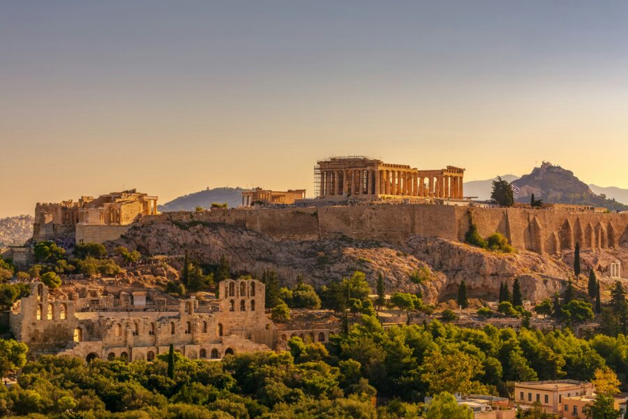 Sunset over Acropolis, featuring Parthenon, Odeon of Herodes Atticus, and lush greenery in Athens.