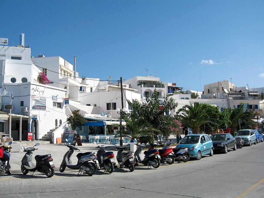 Parked scooters lined up on a street in Adamas, Milos, Greece, showcasing the local transportation scene.