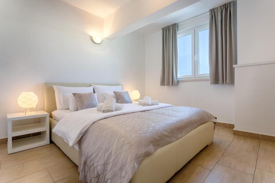 Bright bedroom with white walls and wooden floors, located in Adriatic Queen Rooms & Apartments, Split, Croatia.