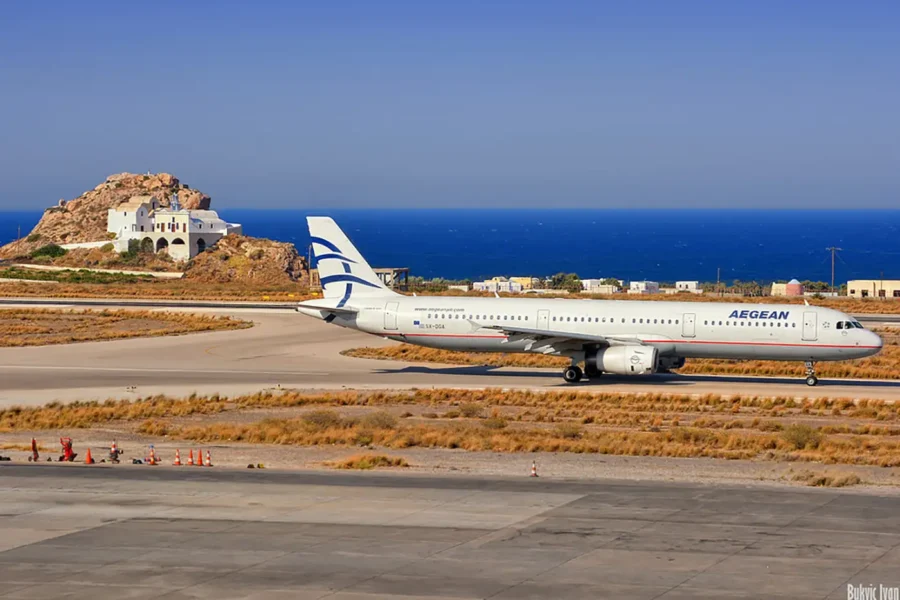 Aegean Airlines plane at Santorini Airport with Mediterranean backdrop.