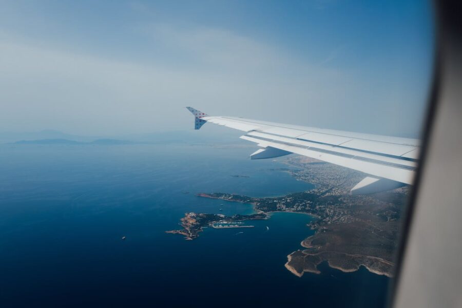 Aerial view of a coastal town, sea, and airplane wing over Mykonos.