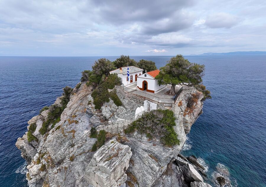 Scenic view of the Chapel of Agios Ioannis in Skopelos, Greece, with its iconic white architecture against a blue sky.