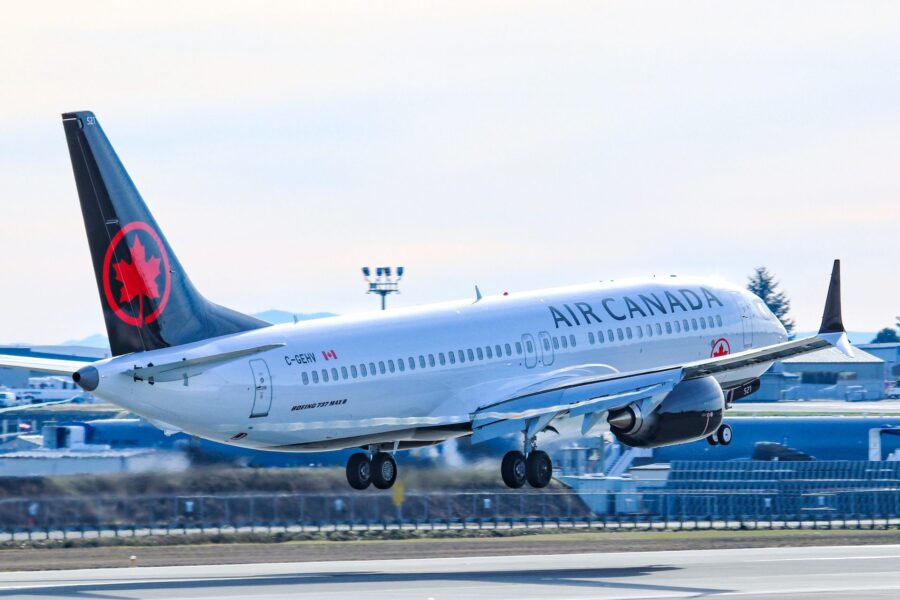 Air Canada Boeing 737 ascending from runway with blue sky backdrop.