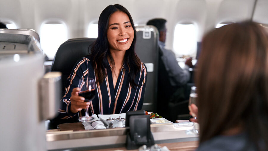 Premium air travel dining: woman enjoys wine in luxurious airplane cabin.