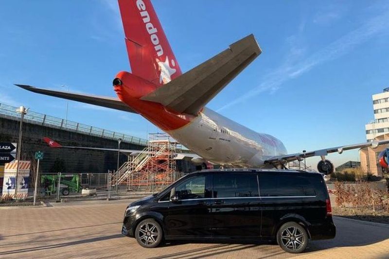 Airplane exhibit with black van in front, aviation museum construction.
