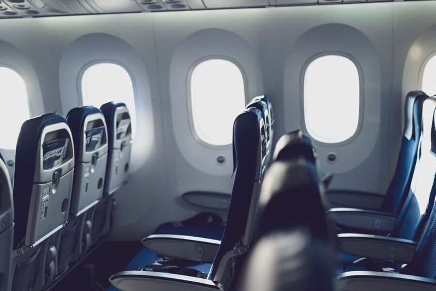 Modern airplane interior, empty navy seats, natural light, economy class, b787 model.