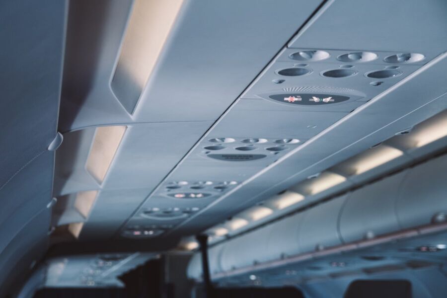 Modern airplane cabin ceiling with ventilation, lighting, and safety indicators.