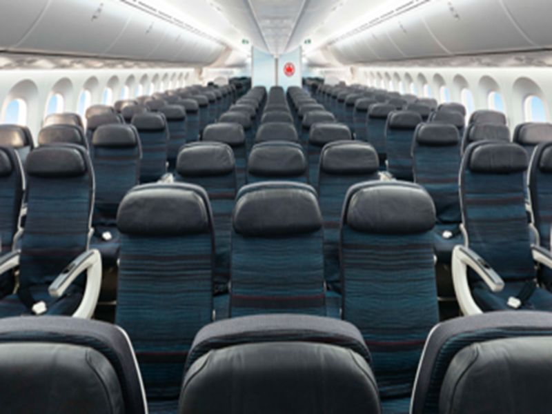 Modern airplane cabin with blue seats, natural light, and spacious layout.