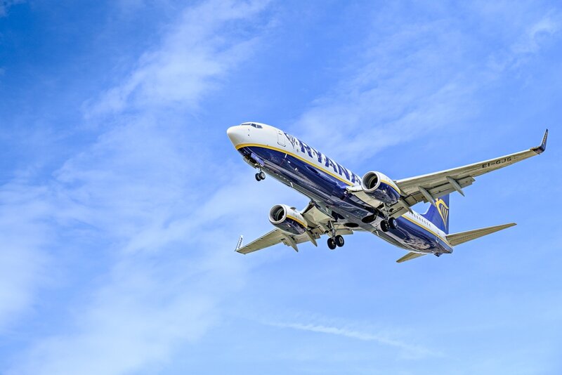 Ryanair airplane landing against blue sky, showcasing vibrant colors and advanced engineering.