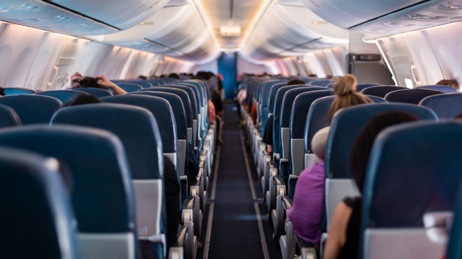 Interior view of airplane seats with passengers seated, showcasing the cabin layout and travel atmosphere.