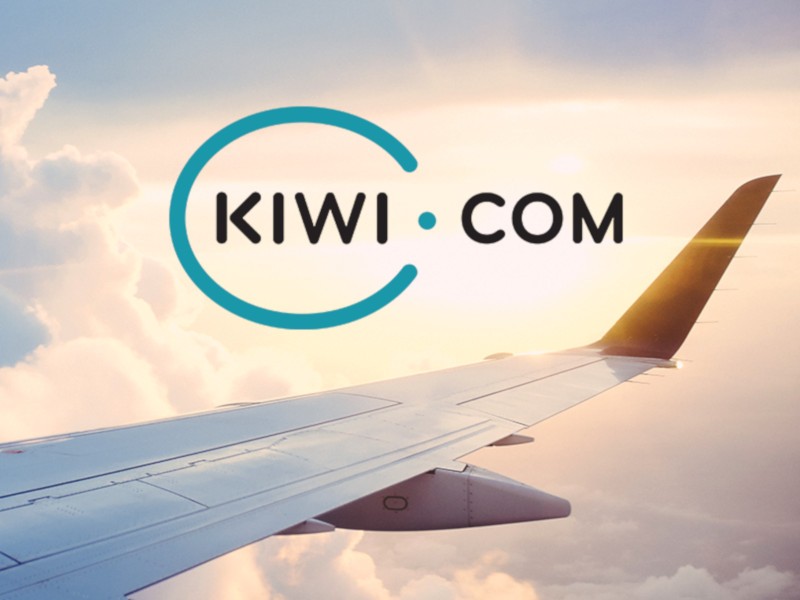 Airplane wing in sky with Kiwi.com logo, evoking travel adventure and brand innovation.
