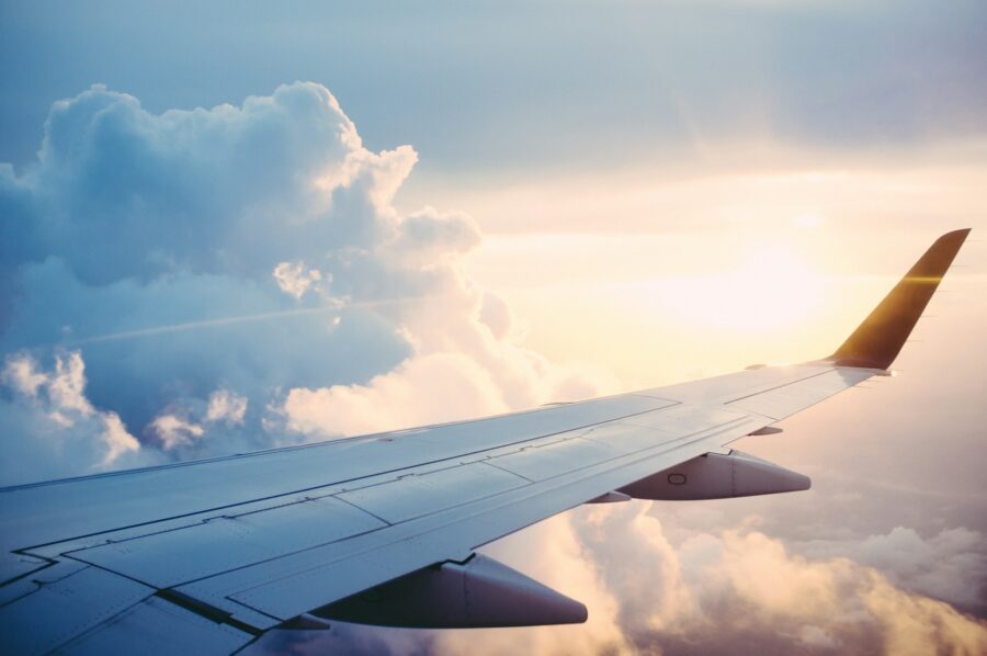Airplane wing at sunset above dramatic cumulus clouds, aerial view with winglet.