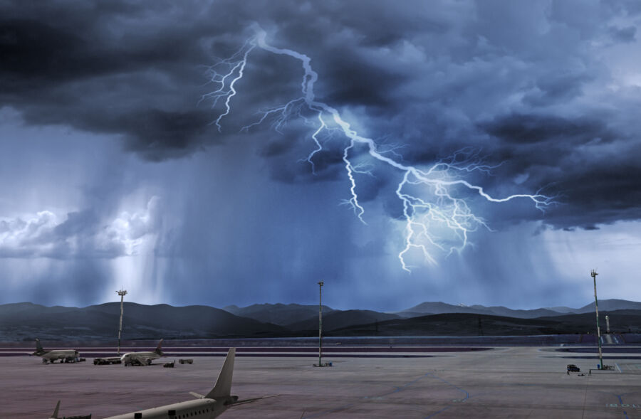 Airport under severe weather conditions, showcasing dark skies, torrential rain, and a prominent lightning bolt