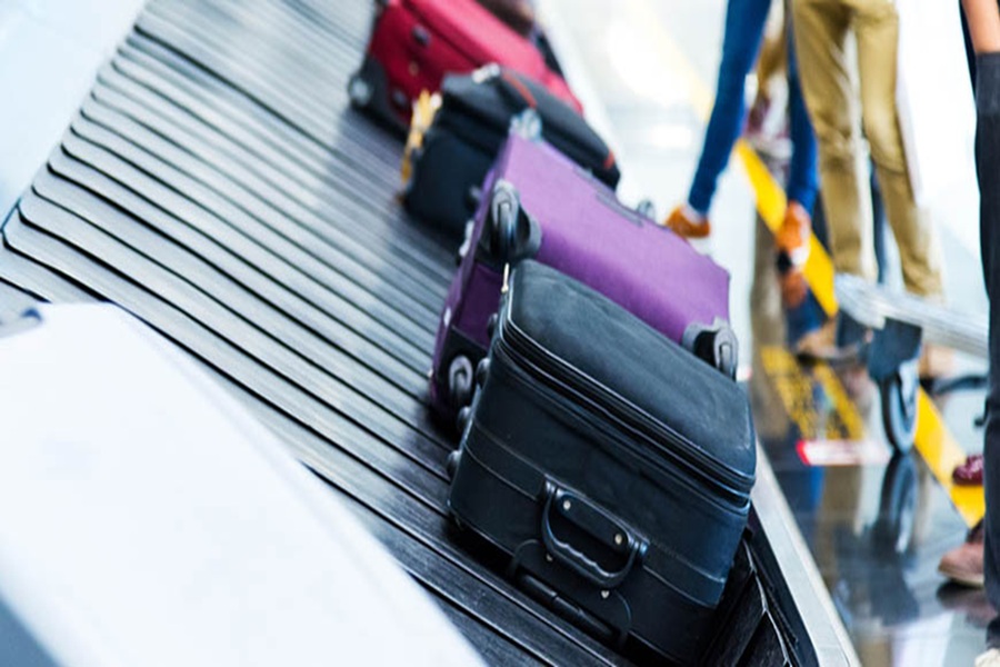 Busy airport luggage carousel with colorful suitcases arriving from flight. Vibrant travel atmosphere.