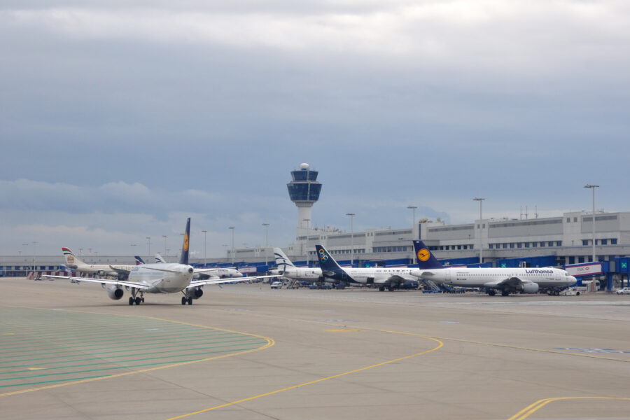 Bustling Athens airport with aircraft, control tower, international airlines, runway, and operations underway.