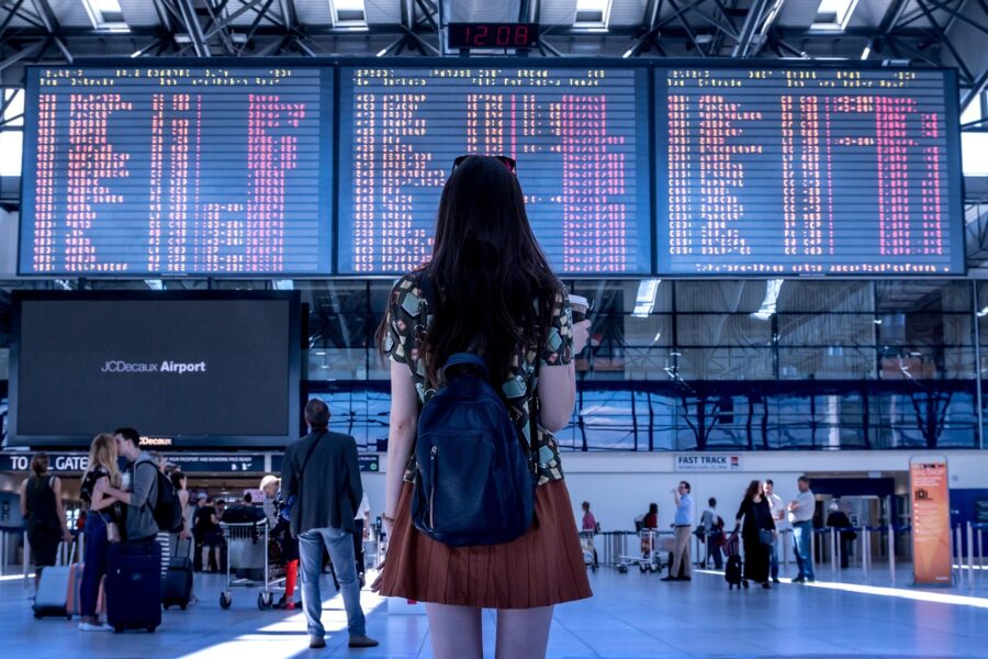 Airport traveler checking flight board amid bustling terminal scene.