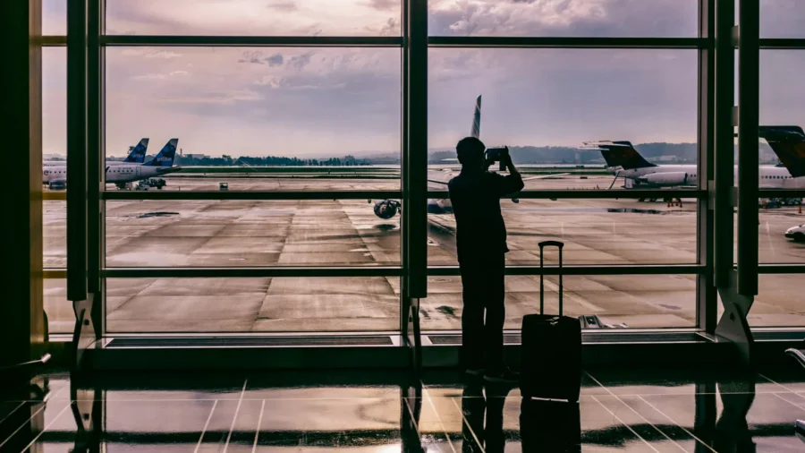 Airport terminal scene with traveler, panoramic runway view, aircraft, and wet tarmac.