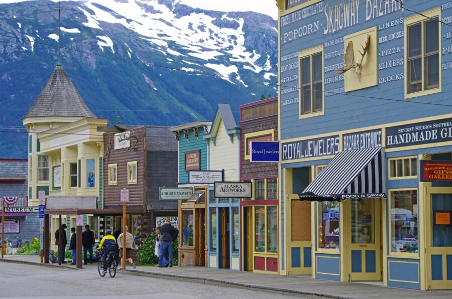 Skagway Alaska main street with colorful historic storefronts, tourist shops and mountain backdrop.