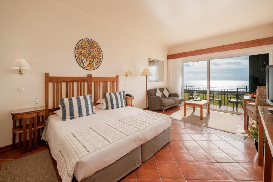 Elegant bedroom with a large bed, offering a breathtaking view of the ocean at Albatroz Beach & Yacht Club, Madeira