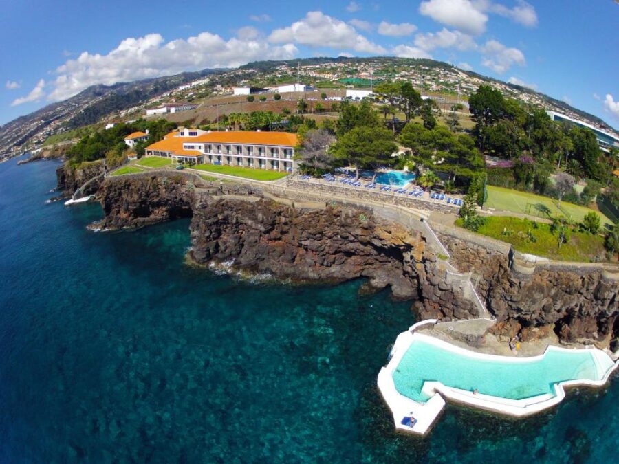 Albatroz Beach & Yacht Club, a hotel perched on a cliff, overlooks the vast ocean, showcasing breathtaking scenery.
