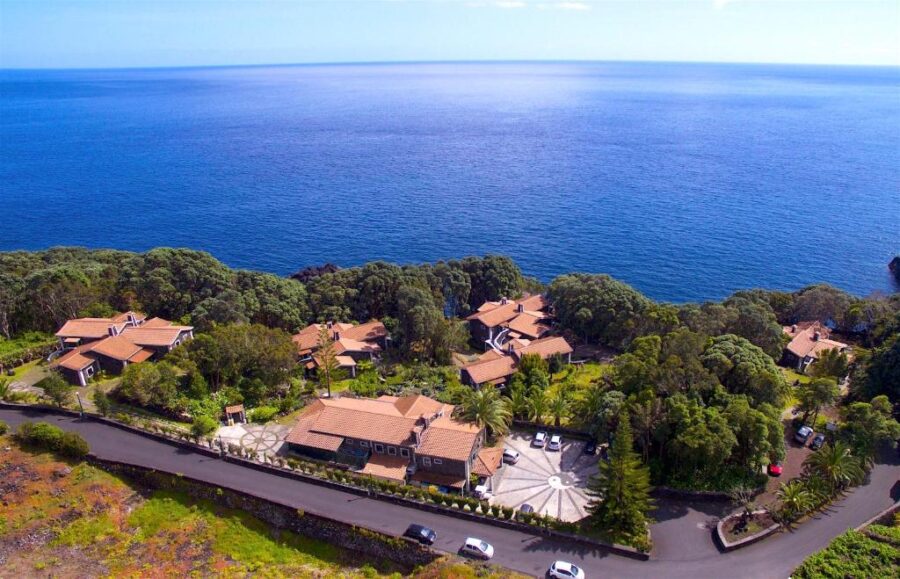 Aerial view of Aldeia da Fonte Hotel, a large house with a stunning ocean backdrop.
