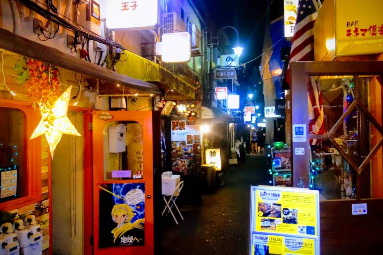 Golden Gai Tokyo alley with lantern-lit bars and street-food stalls at night.