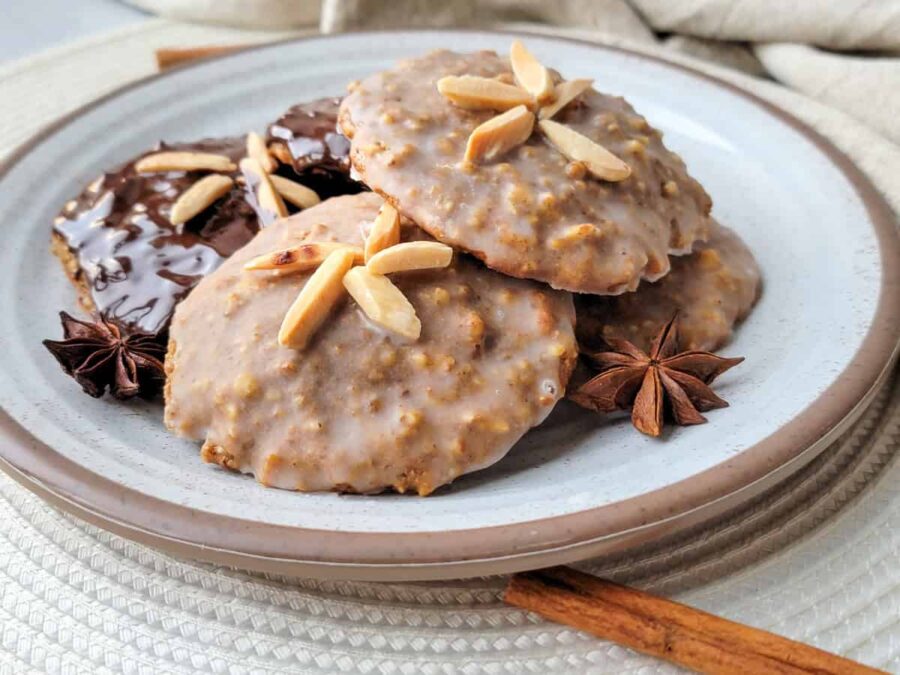 Almond-glazed Lebkuchen cookies with slivered almonds, star anise and cinnamon on ceramic plate.
