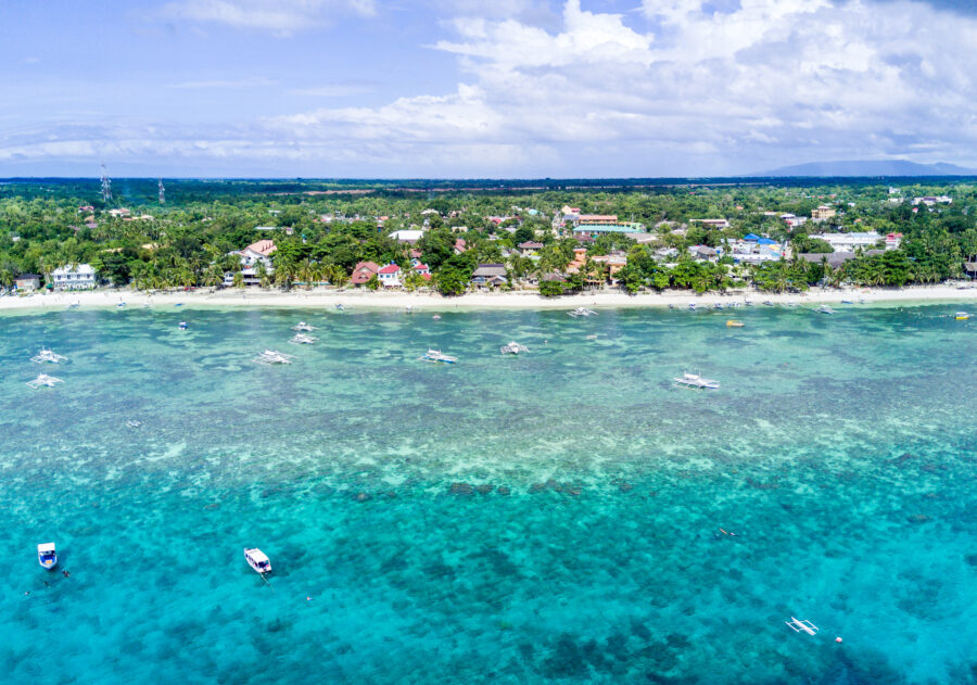 Aerial view of Alona Beach in Panglao, highlighting its soft white sand and vibrant blue sea, framed by tropical scenery.