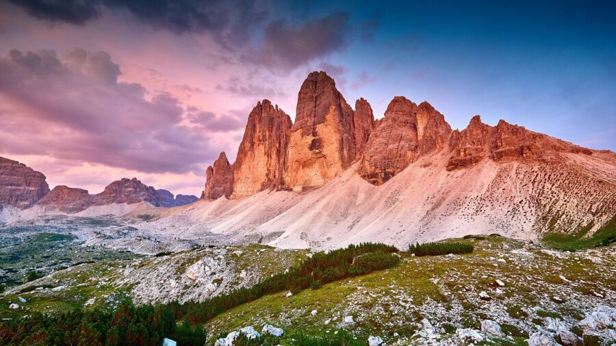 Dolomites sunset over jagged alpine cliffs and meadow.