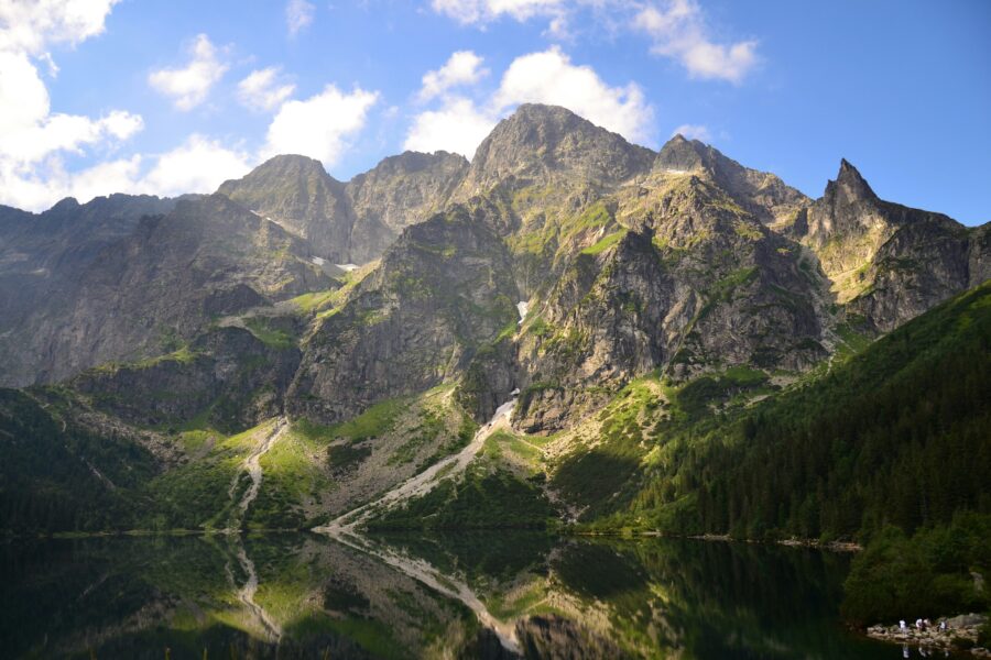 Alpine lake reflection of rugged mountain peaks and conifer forest.