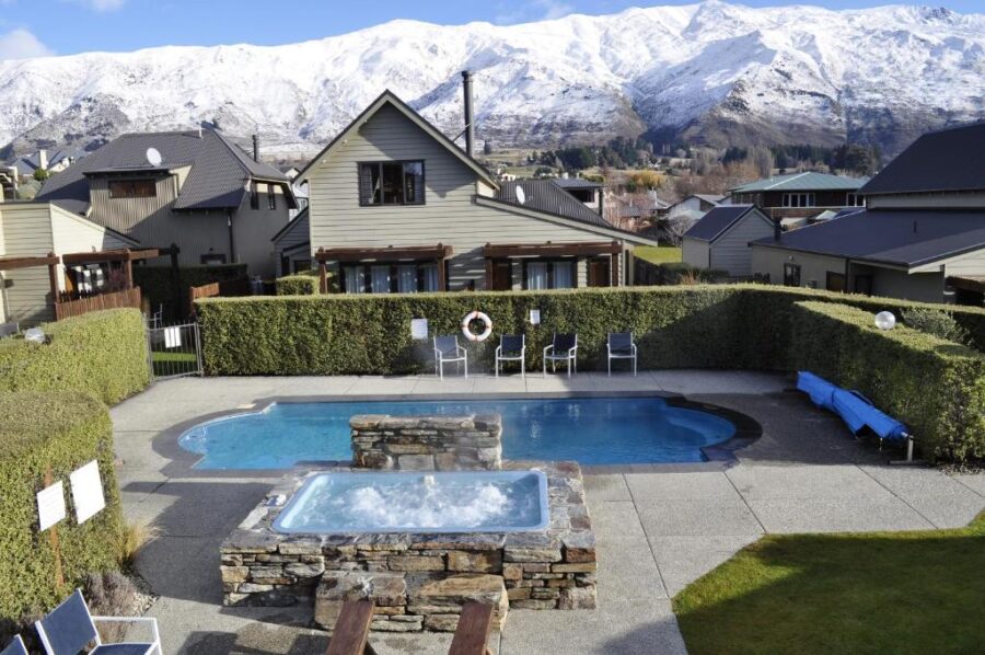 Luxury alpine apartments with heated pool and hot tub overlooking snowy Wanaka mountain range.