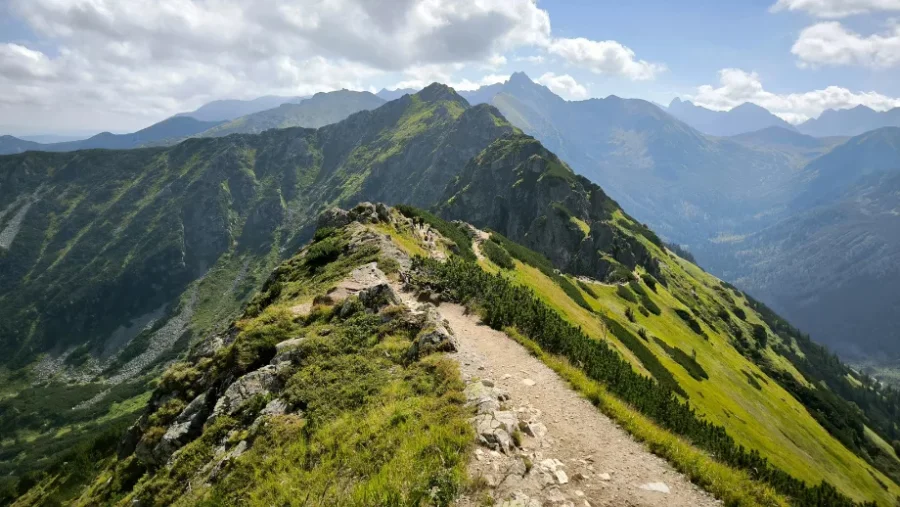 Alpine ridge hiking trail in Tatra National Park with distant jagged mountain peaks.