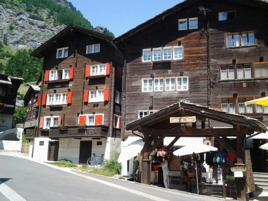 Charming building featuring many windows and a wooden roof, located in the scenic Alpine Village of Zermatt.