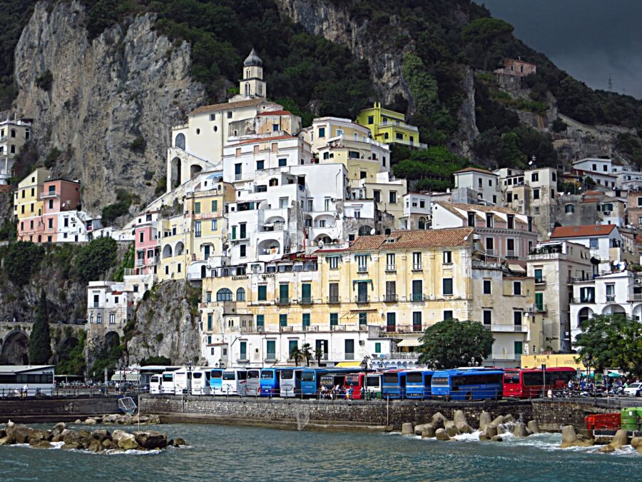 Picturesque mountain featuring various buildings, highlighting the Amalfi Coast Buses in a vibrant setting.