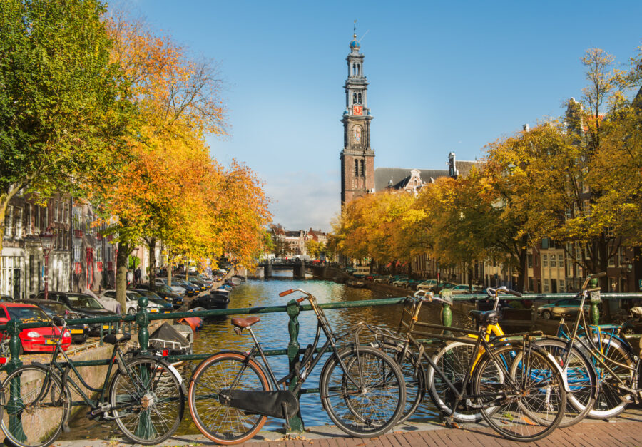Scenic view of an Amsterdam canal with the iconic Westerkerk tower in the background, surrounded by historic buildings.