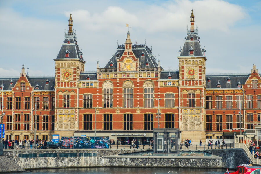 Exterior view of Amsterdam Central Station, showcasing its distinctive architecture and prominent clock tower.