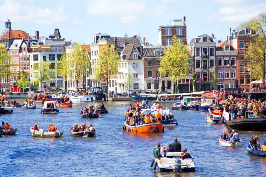 Crowds of people in orange clothing joyfully celebrating Kings Day in Amsterdam
