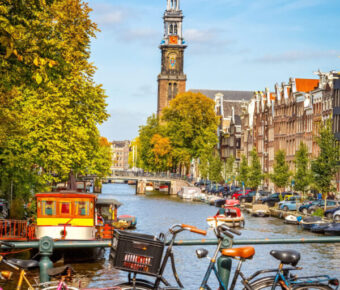 Traditional old buildings and boats line the canals of Amsterdam, showcasing the city's historic architecture and charm.