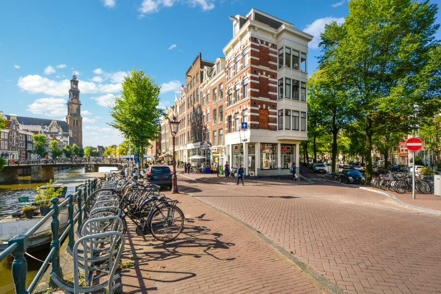 Dutch street in Amsterdam features bicycles by a canal, with the Westerkerk church tower visible in the background