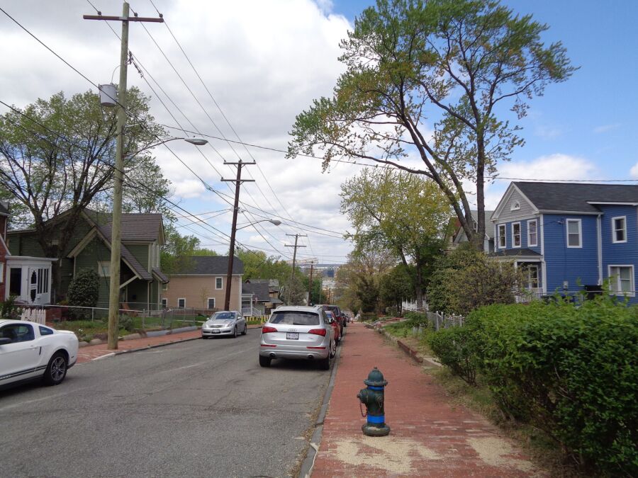 Anacostia street scene in Washington DC, featuring residential buildings and trees lining the sidewalk.
