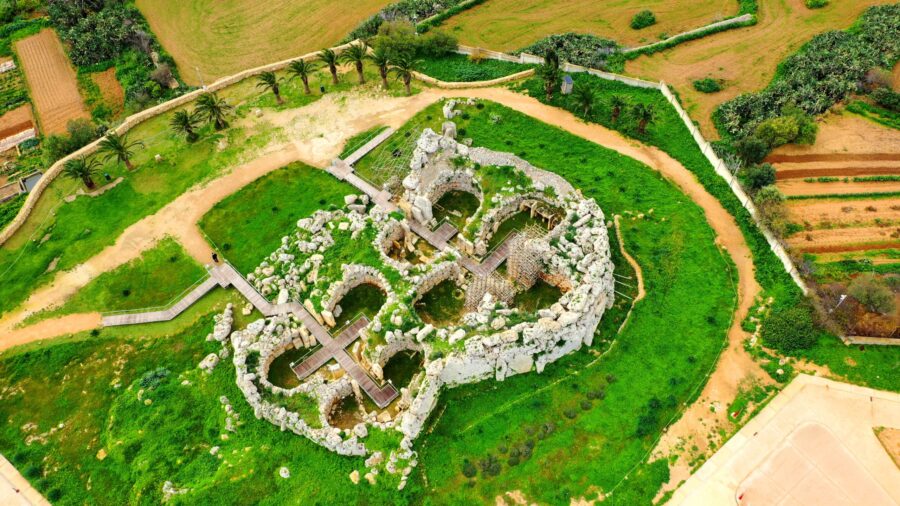Aerial view of Ggantija Temples prehistoric limestone ruins with wooden walkways and surrounding green fields.